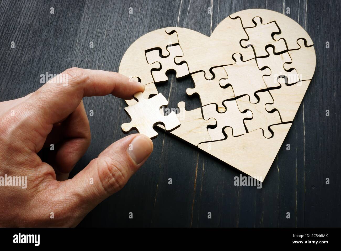 Die Hand hält ein Puzzleteil in Form eines Herzens. Stockfoto