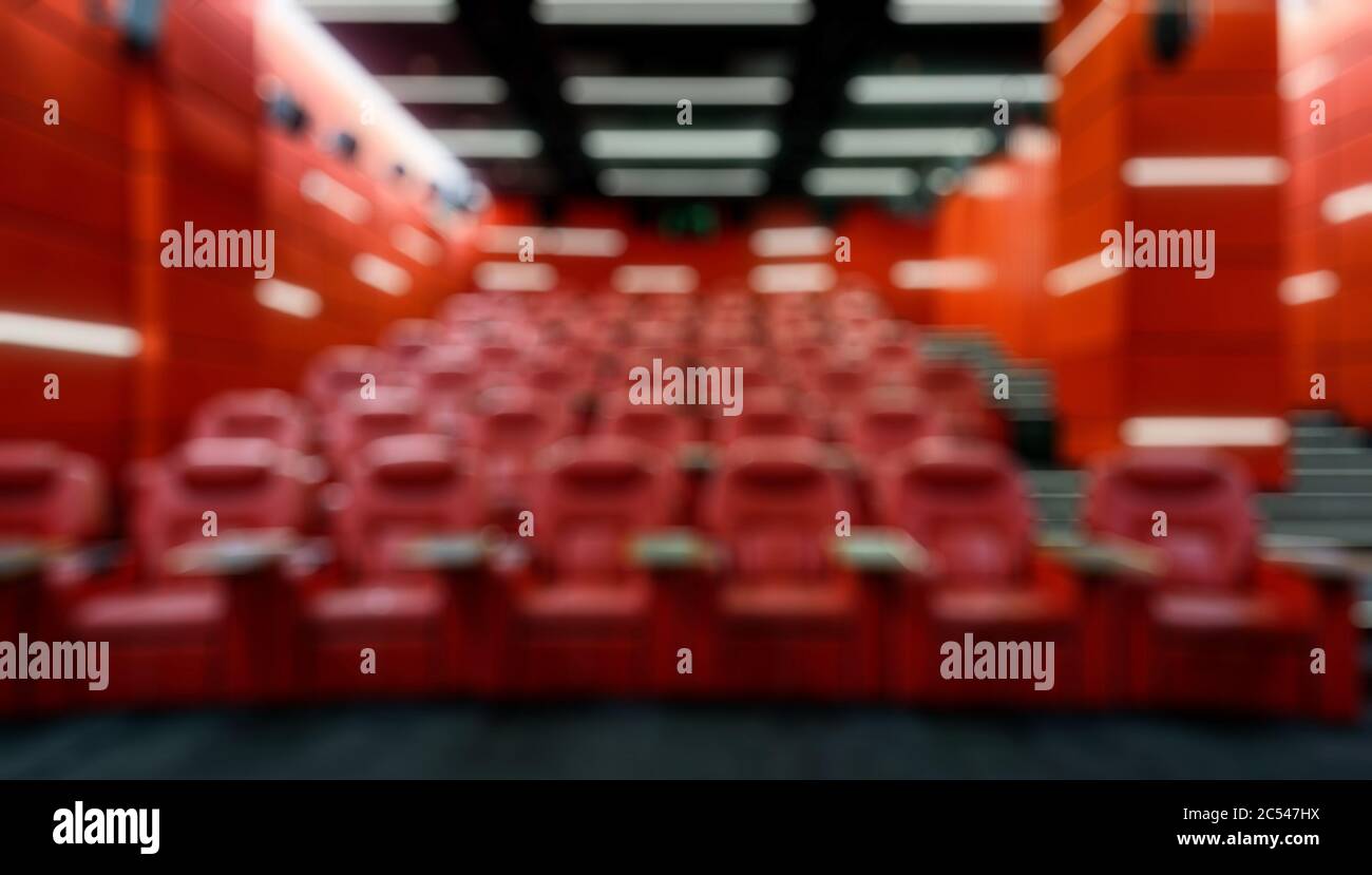 Panoramablick auf einen leeren Kinosaal als kreative abstrakte Unschärfe-Hintergrund. Im roten komfortablen Theater. Modernes Kinosaal-Design Stockfoto