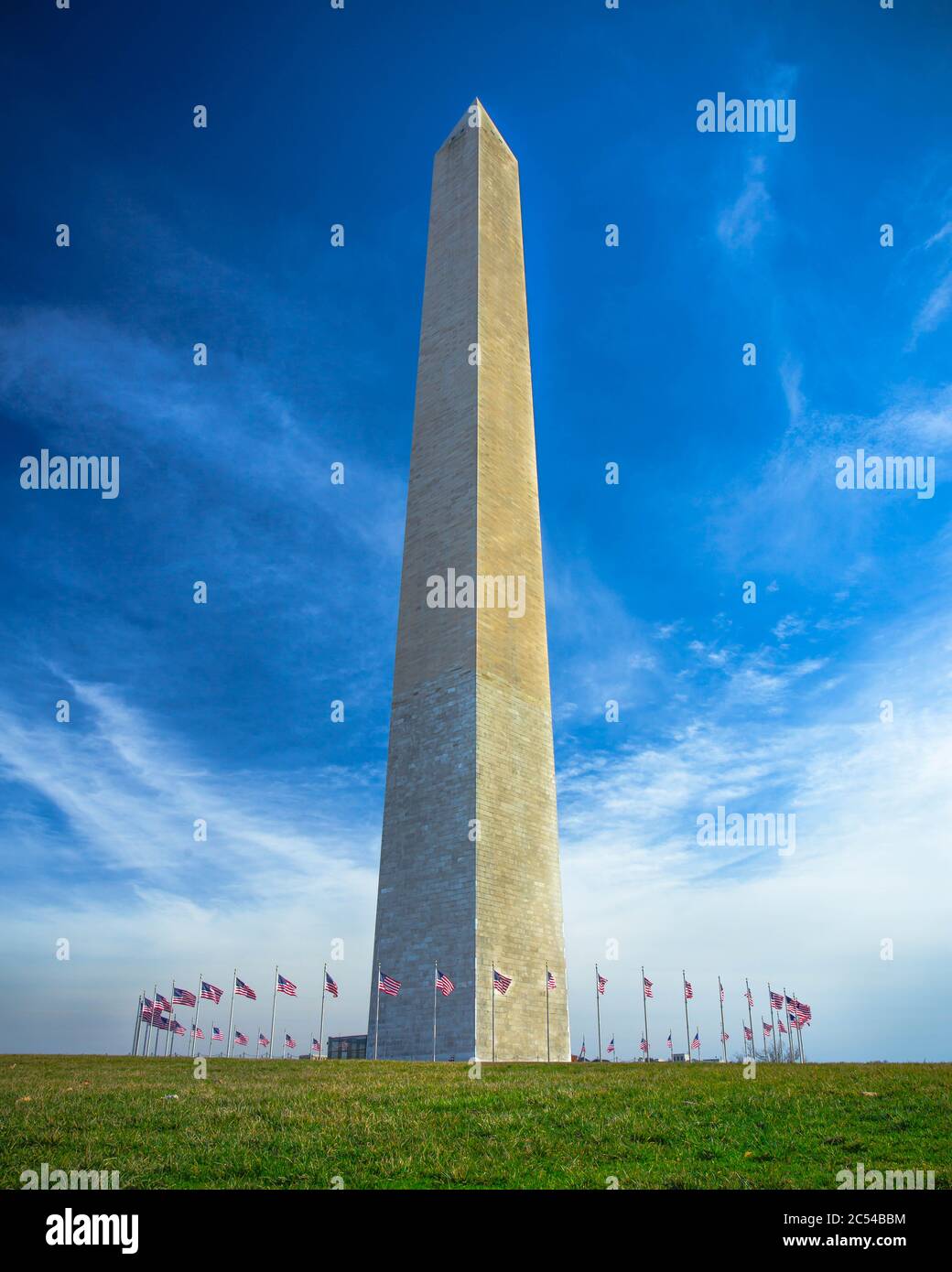 Das Washington Monument in Washington, D.C. umgeben von amerikanischen Flaggen vor blauem Himmel Stockfoto
