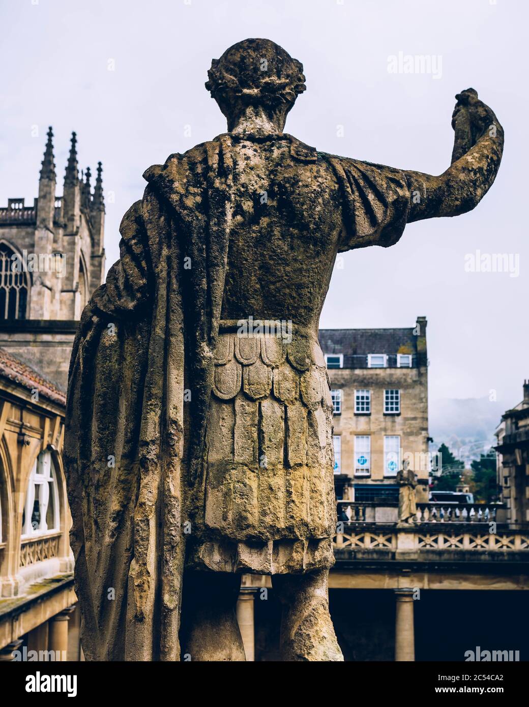 Die Rückseite einer römischen Statue in den römischen Bädern mit Bath Abbey im Hintergrund in Bath, Großbritannien Stockfoto