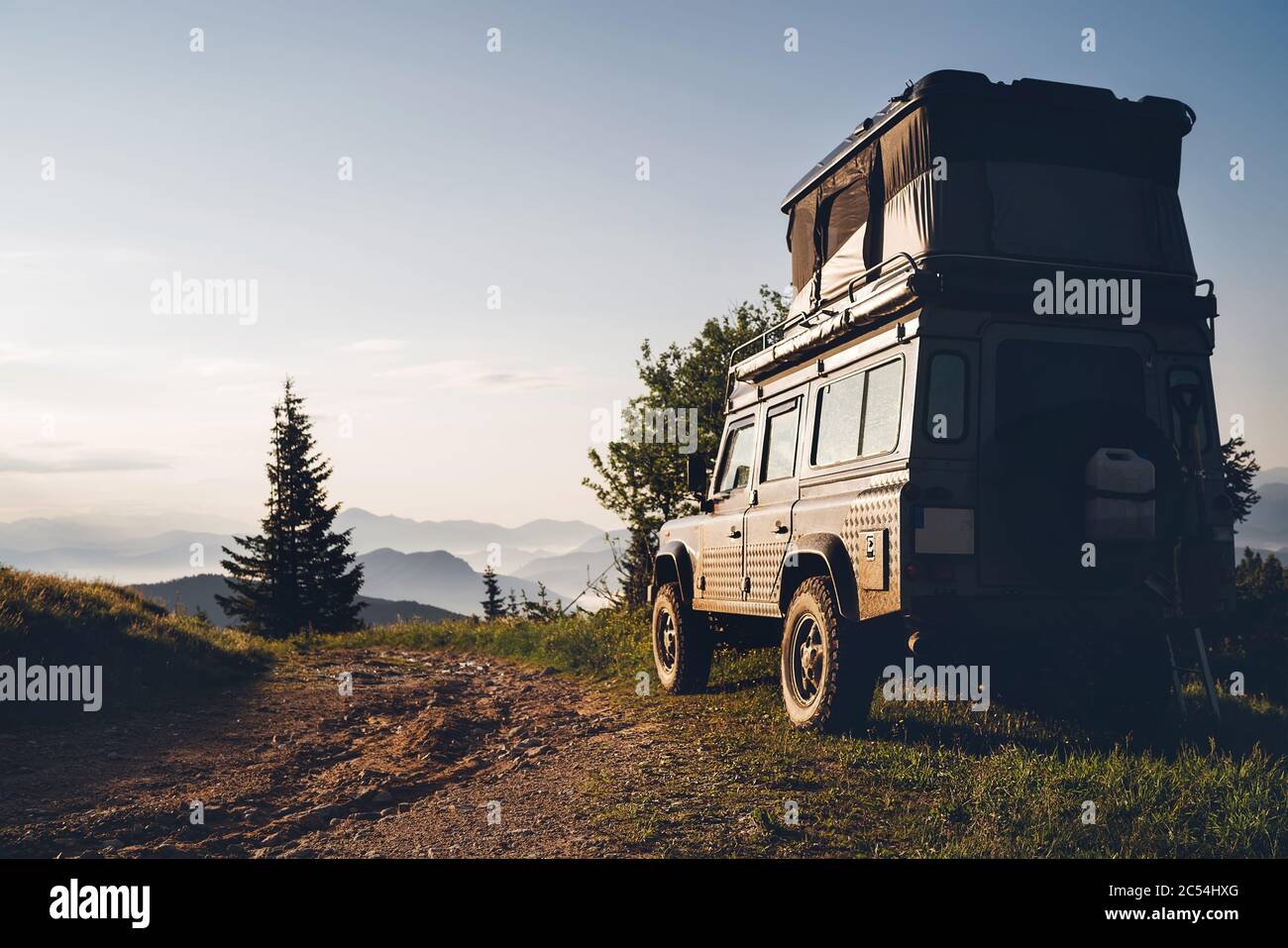 Offroad 4x4 mit Pop oben höhenverstellbaren Dach Schlafzelt Abstellraum Fahrzeug auf der schmutzigen Landstraße in den slowakischen Bergen in den frühen Morgenstunden sunri Stockfoto