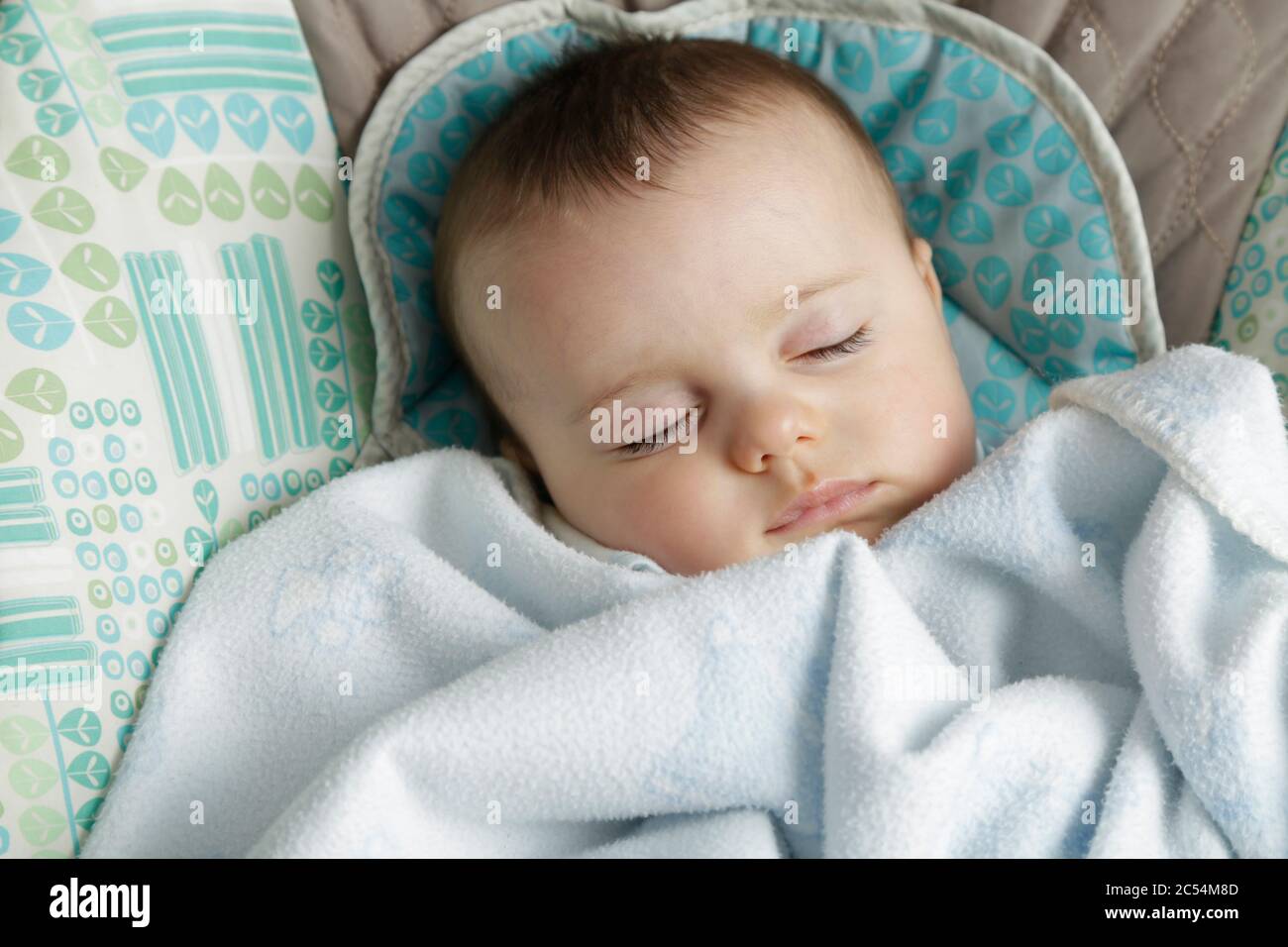 Baby schläft in einem Schaukelstuhl mit einer Decke bedeckt. Stockfoto
