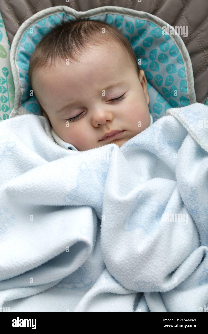 Baby schläft in einem Schaukelstuhl mit einer Decke bedeckt. Stockfoto