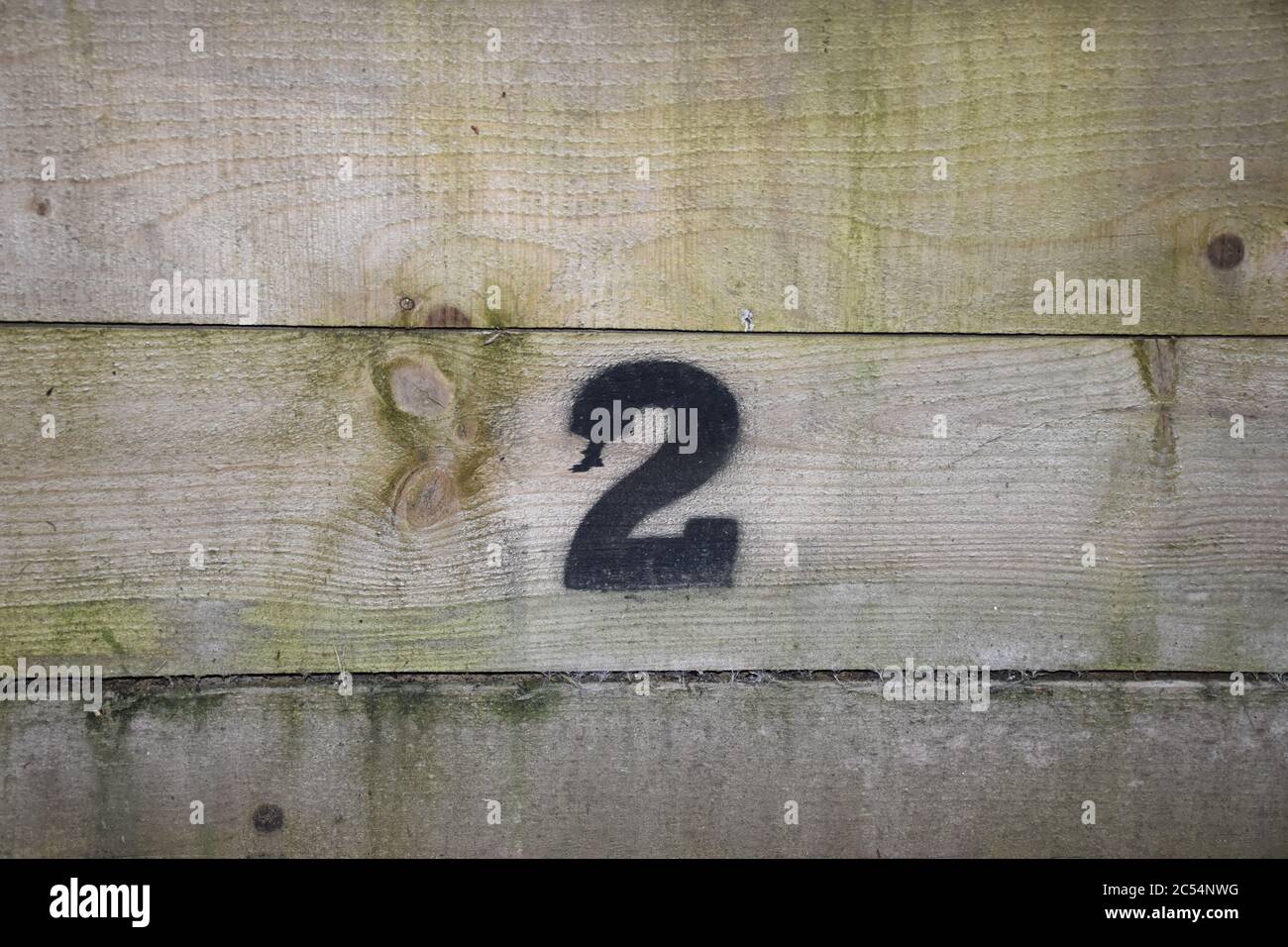 Schwarze Nummer zwei (2) auf Holzwand. Erstellt durch Schablone und Sprühfarbe. Stockfoto