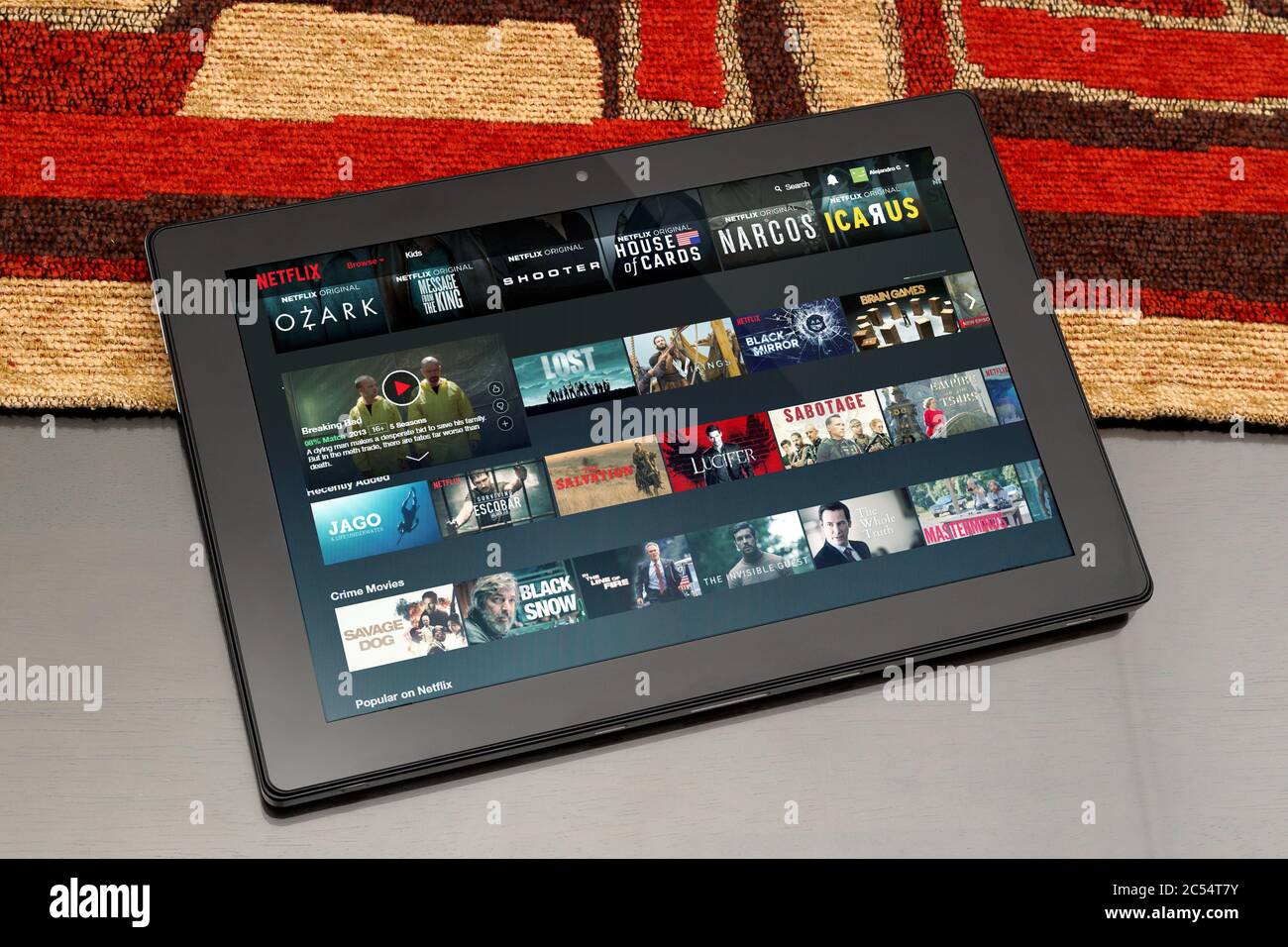 Tablet über Tisch. Netflix´s Website ist auf dem Bildschirm geöffnet. In diesem können Miniaturansichten von Filmen und Serien sehen. Stockfoto