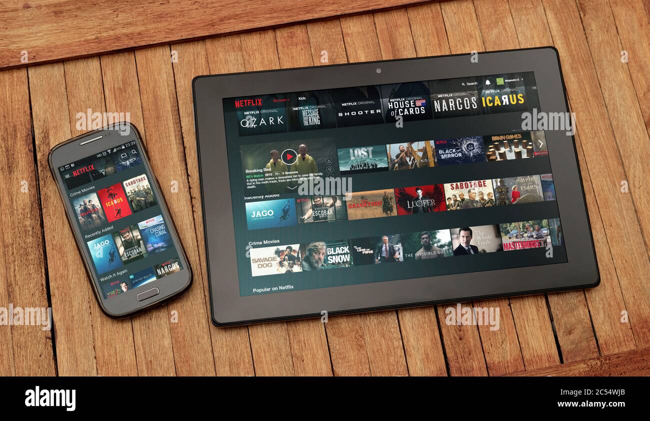 Netflix´s Website geöffnet auf Tablet und Handy-Bildschirm. In diesen können Miniaturansichten von Filmen und Serien sehen. Stockfoto