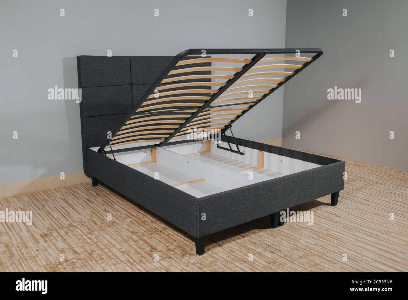 Graues Bett mit einem Stauraum, der durch Anheben des enthüllt wird Boden  aus Holzlatten Stockfotografie - Alamy