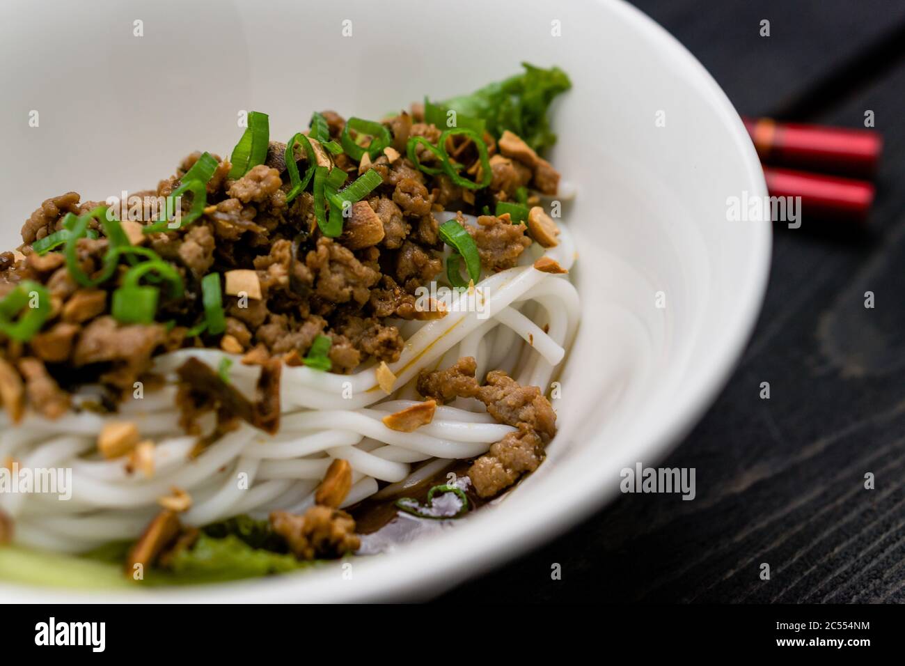 Dan Dan Noodles Nahaufnahme. Dan Dan Noodles ist ein würziges Szechuan-Gericht, das häufig in chinesischen Straßenessen zu finden ist. Zutaten sind dicke Reisnudeln Stockfoto