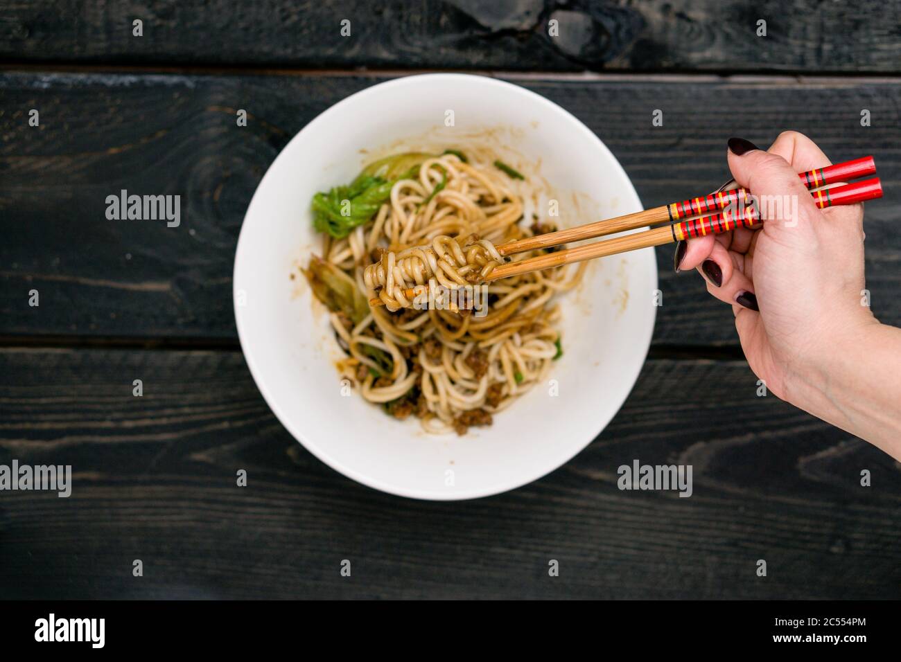Dandan Nudeln auf Essstäbchen. Dan Dan Noodles ist ein würziges Szechuan-Gericht, das häufig in chinesischen Straßenessen zu finden ist. Zutaten sind dick Reis n Stockfoto