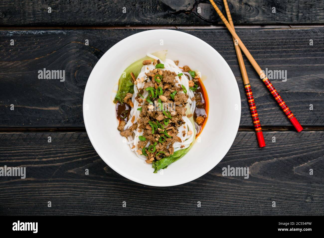 Dan Dan Noodles Draufsicht. Dan Dan Noodles ist ein würziges Szechuan-Gericht, das häufig in chinesischen Straßenessen zu finden ist. Zutaten sind dicke Reisnudeln Stockfoto