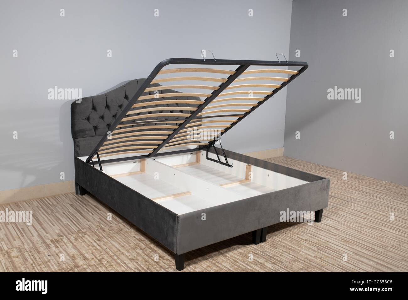 Graues Bett mit einem Stauraum, der durch Anheben des enthüllt wird Boden  aus Holzlatten Stockfotografie - Alamy