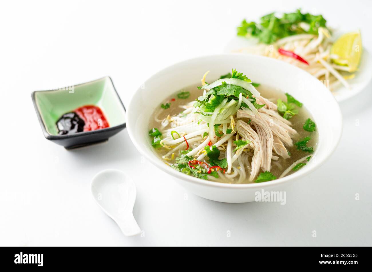 Vietnamesische Pho-Suppe auf weißem Hintergrund. Diese Pho-Suppe ist ein klassisches, authentisches vietnamesisches Essen und wird in einer weißen Schüssel mit Hühnerbrühe und viel f serviert Stockfoto
