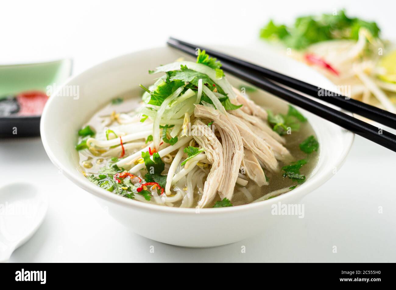 Vietnamesische Pho Nudelsuppe Schüssel Nahaufnahme. Diese Pho-Suppe ist ein klassisches, authentisches vietnamesisches Essen und wird in einer weißen Schüssel mit Hühnerbrühe und viel f serviert Stockfoto