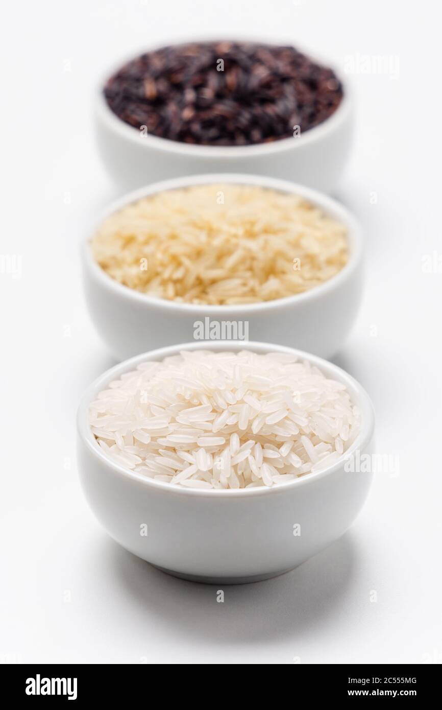 Reiskorntypen Vordergrund Fokus. 3 Reissorten mit Fokus auf den weißen jasmin-Reis, während der Basmati und der schwarze Reis dahinter verschwommen sind. Reis i Stockfoto