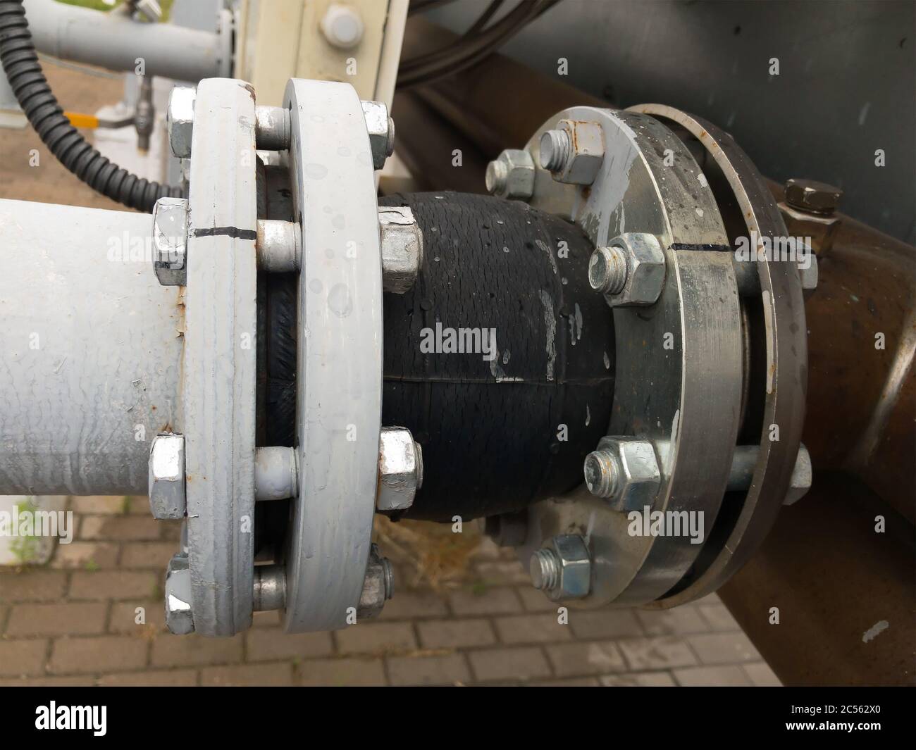 Alte grau lackierte Gummidehnungsfuge mit Rissen in der Pipeline in der industriellen Produktionslinie. Selektiver Fokus. Stockfoto