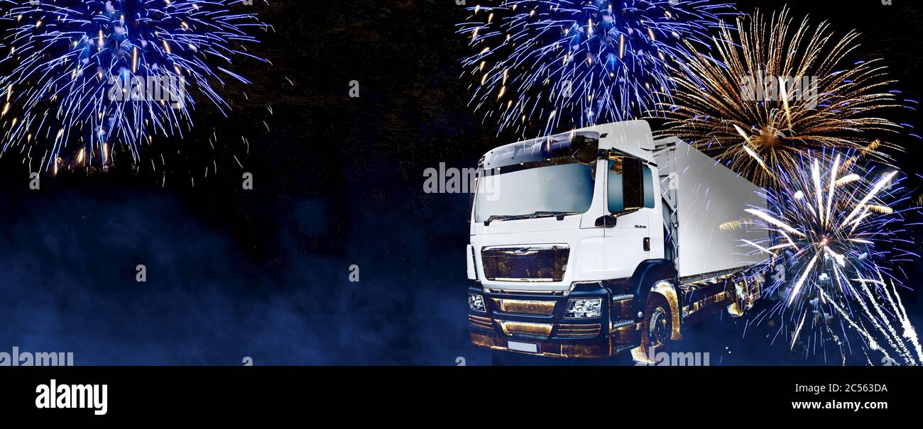 Lastwagen in der Nacht mit Feuerwerk im Hintergrund. Neujahrswünsche mit Feuerwerk und Platz für Text für Logistikunternehmen oder Spediteure Stockfoto
