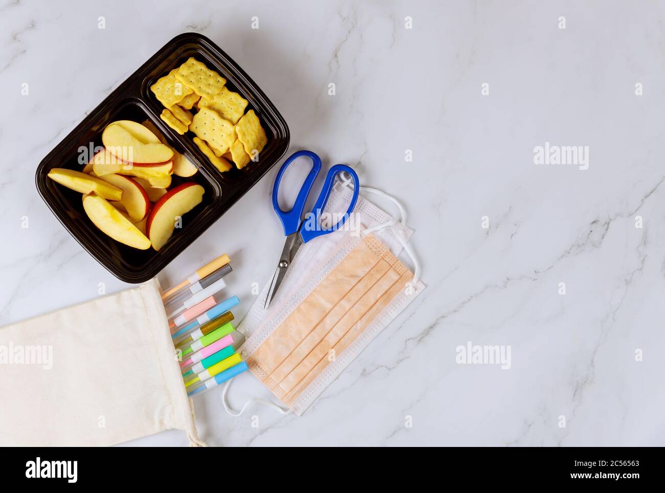 Lunchbox mit Apfel, Cracker und Schulbedarf. Draufsicht. Stockfoto