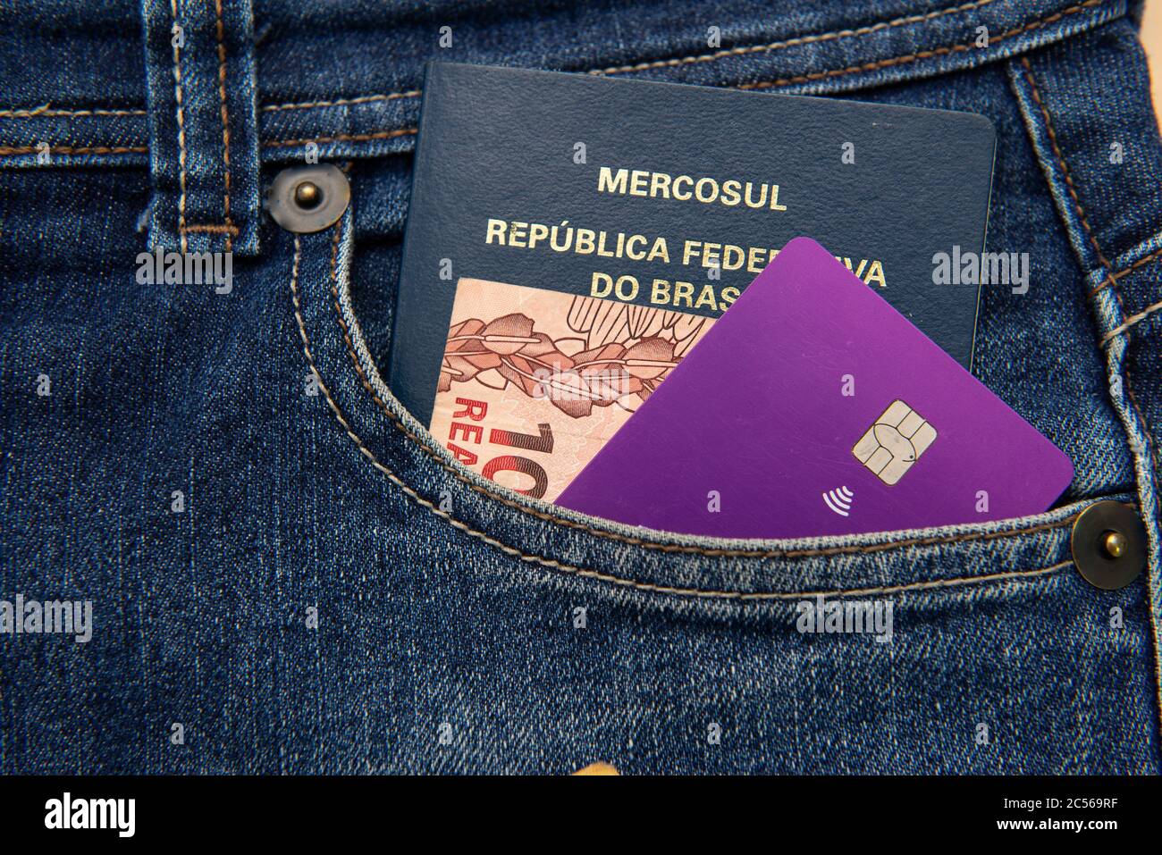 Nahaufnahme von brasilianischen Pass, Banknoten und Kreditkarte in Hosentasche. Übersetzen: Mercosur - Föderative Republik Brasilien - Pass. Stockfoto