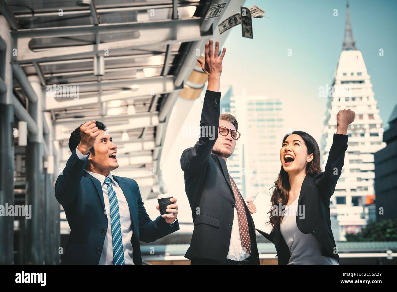 Portrait of Business Team Raising Arms Feiern und werfen Geld auf verschwommenen Stadthintergrund. Erfolgskonzept für Unternehmen. Vintange-Ton Stockfoto