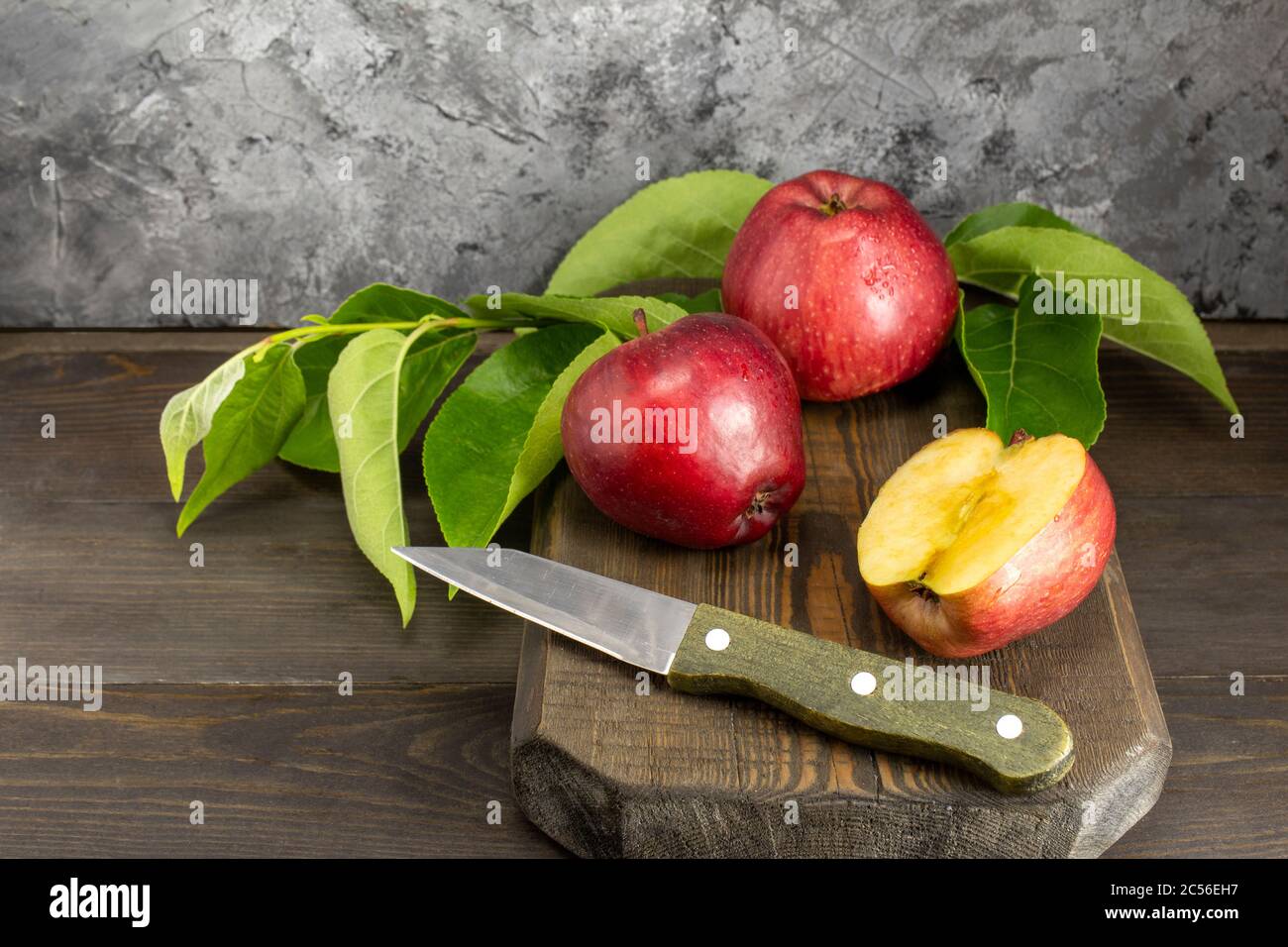 Saftige reife rote Äpfel und auf Holztisch in Scheiben schneiden. Äpfel schneiden Messer auf Holz Schneidebrett. Stockfoto