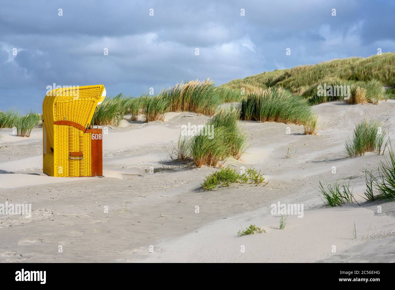 Deutschland, Niedersachsen, Ostfriesland, Juist, Strandliegen isoliert am Rande der Dünen. Stockfoto