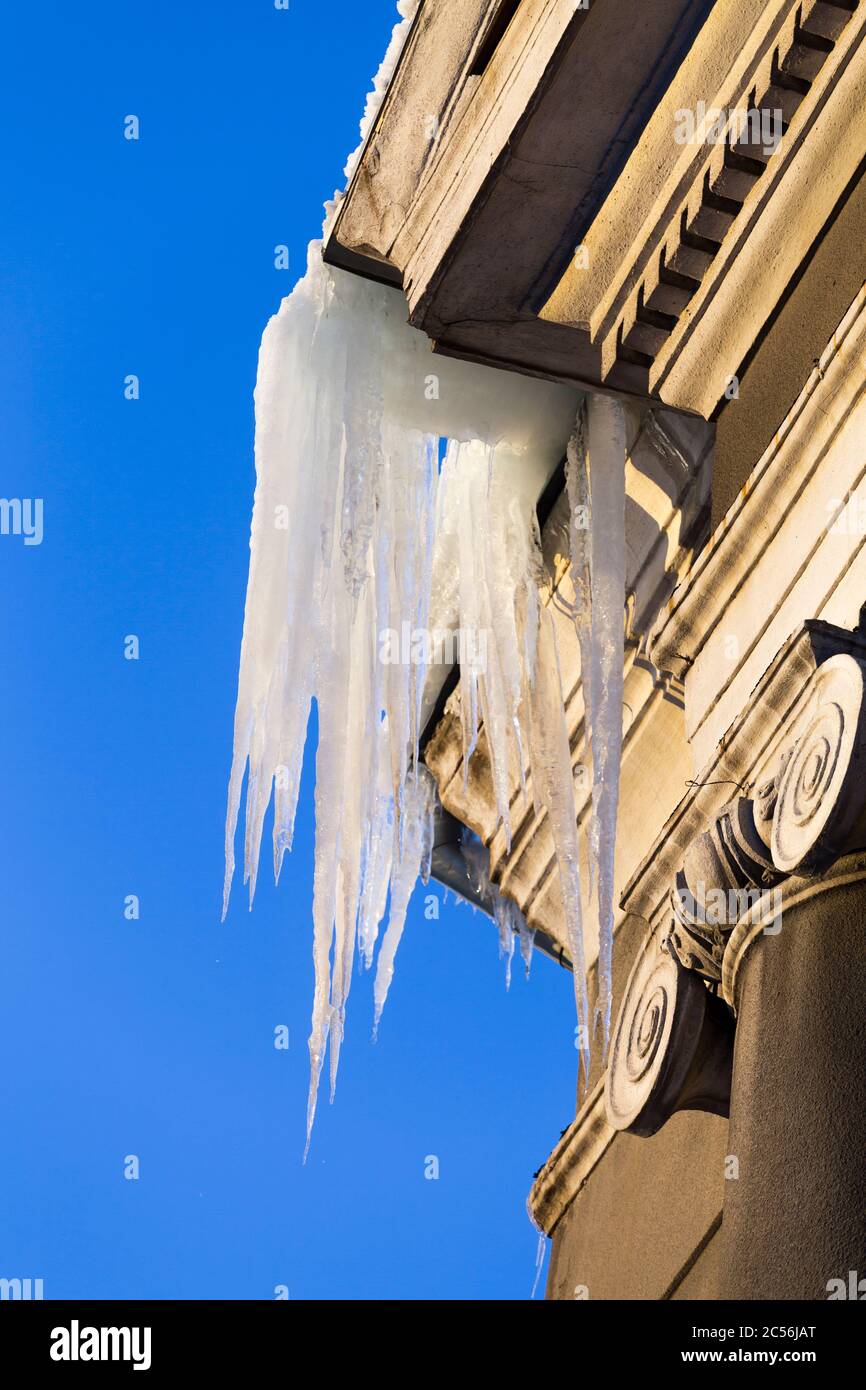 Große Eiszapfen hängen von einem Hausdach. Gefährliche große Eiszapfen. Stockfoto