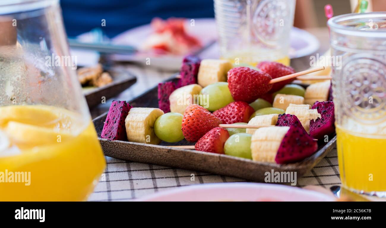 Nahaufnahme von saisonal frischen, gesunden Früchten auf dem Tisch, die bereit sind, von Menschen in der Umgebung zu essen - Saisonkonzept und Vitamine für gesunde Lebensmittel Stockfoto