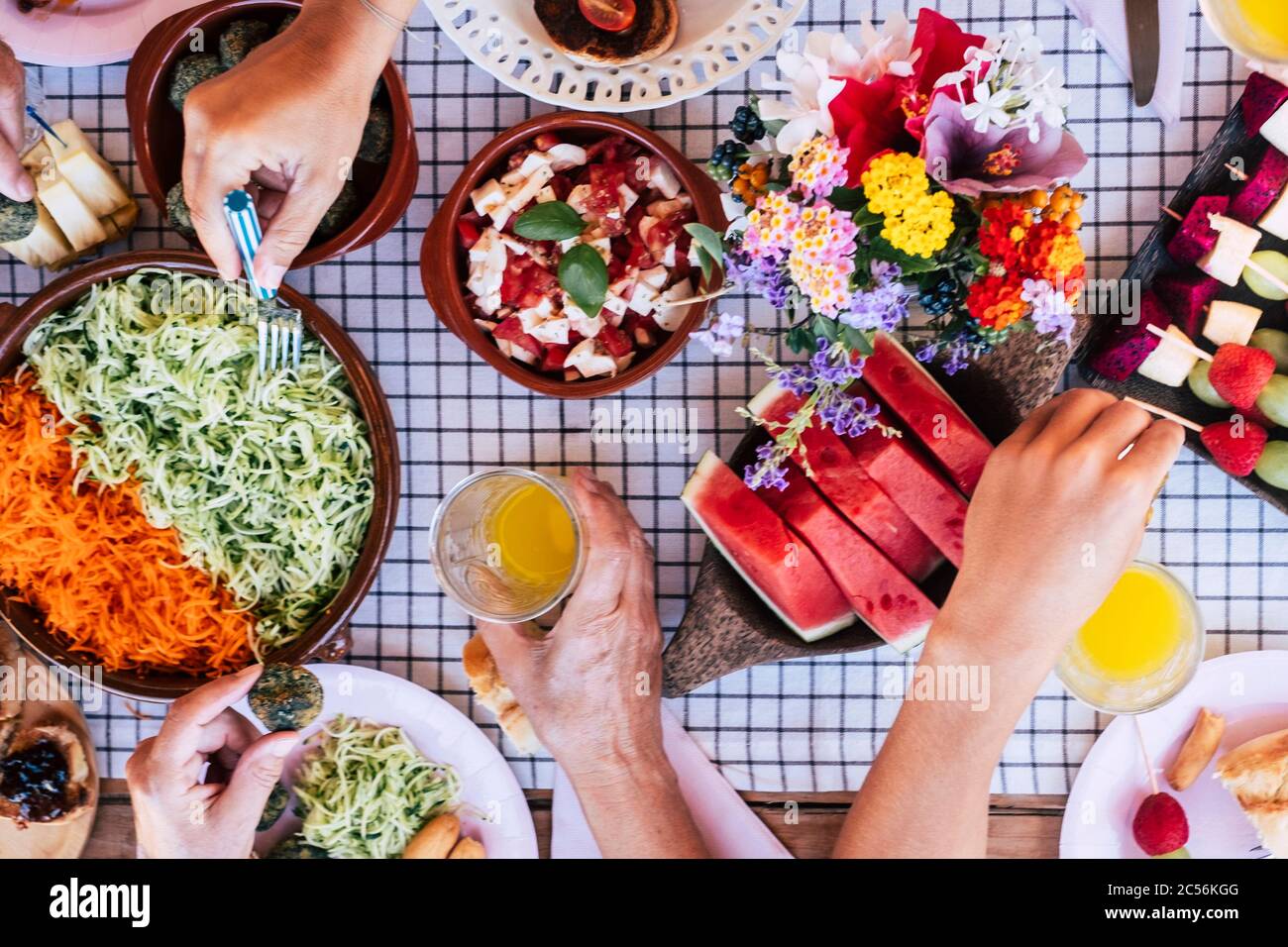 Draufsicht über eine Gruppe von Freunden, die zusammen Spaß mit einem gesunden vegetarischen frischen saisonalen Brunch haben - bunte und energische Speisen zum Essen mit Frie Stockfoto