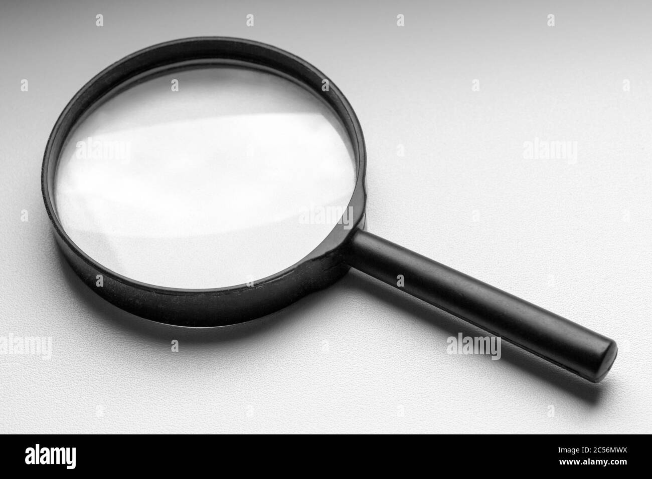 Eine schwarze Lupe liegt auf einer weißen Fensterbank. Stockfoto