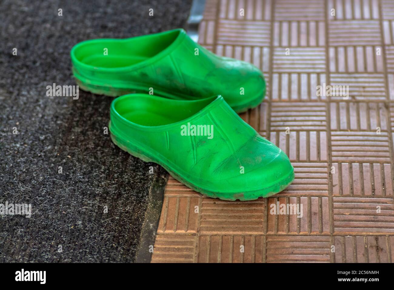 Grüne Gummischuhe stehen auf der Veranda des Hauses. Stockfoto