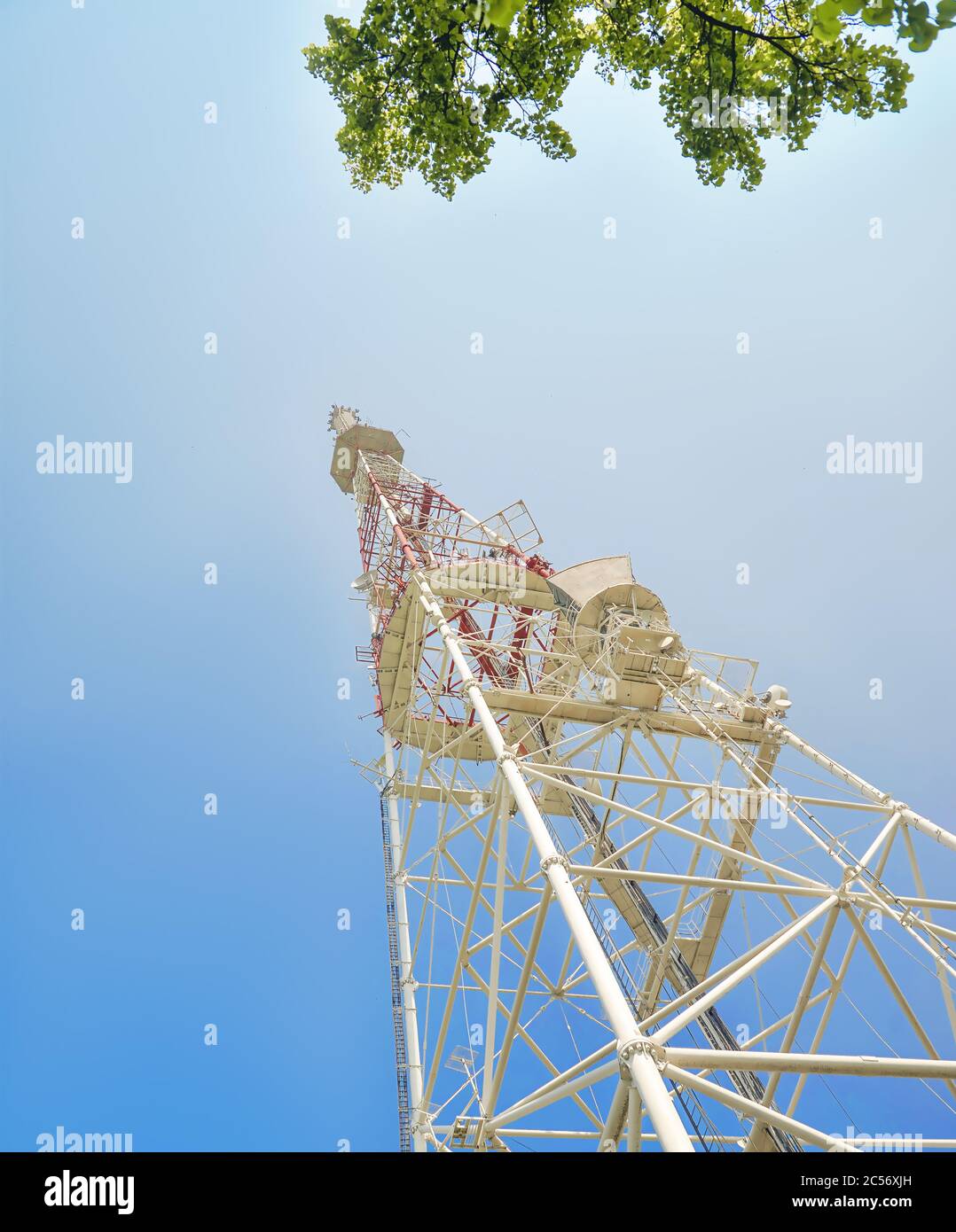 Rot-weißer Turm der Kommunikation mit mit vielen verschiedenen Antennen unter klarem Himmel. Stockfoto