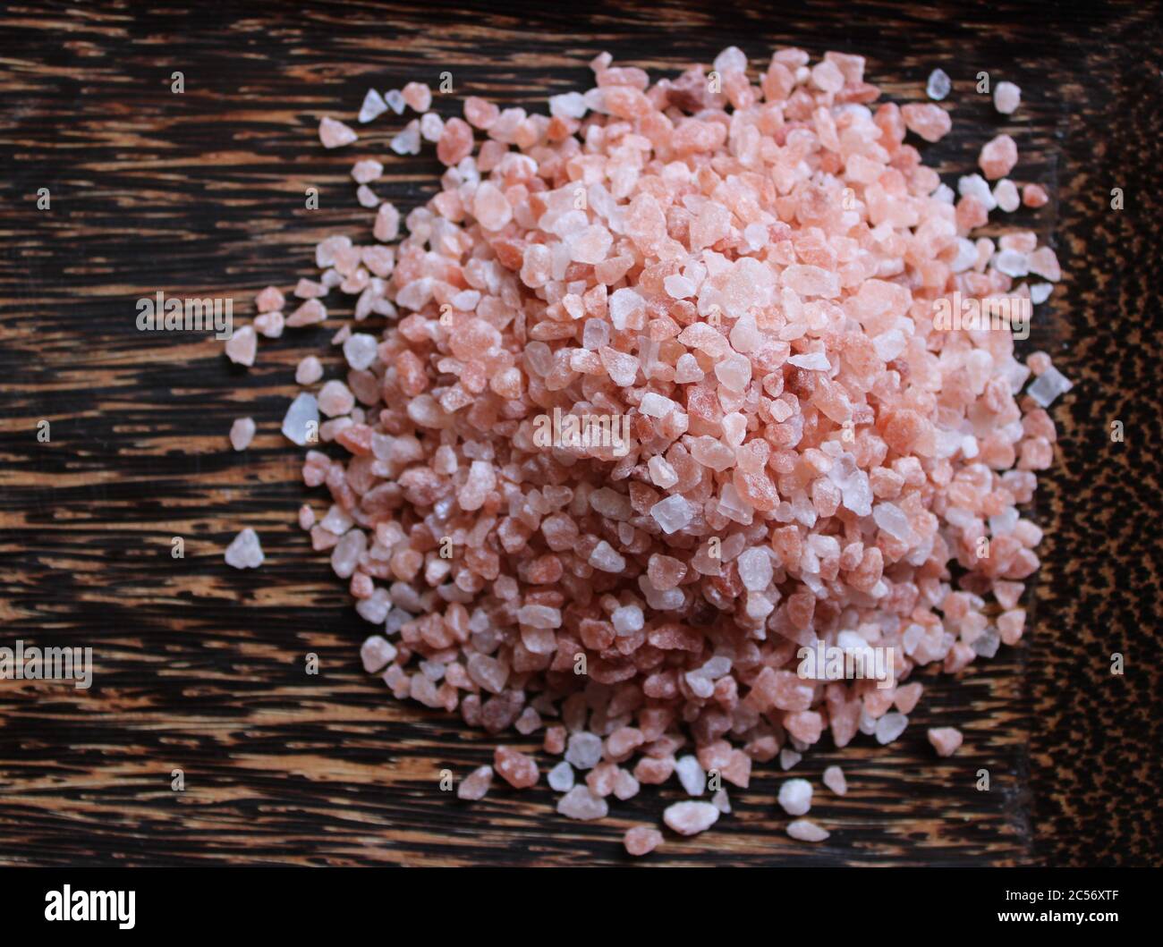 Haufen Himalaya rosa Salz Granulat auf einem dunklen Holztablett Stockfoto