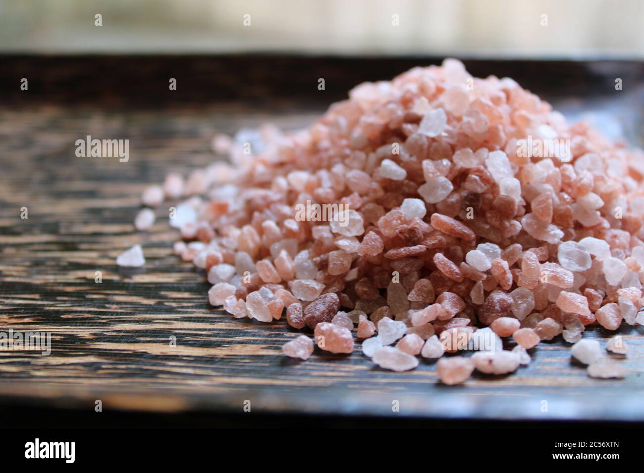 Haufen Himalaya rosa Salz Granulat auf einem dunklen Holztablett Stockfoto