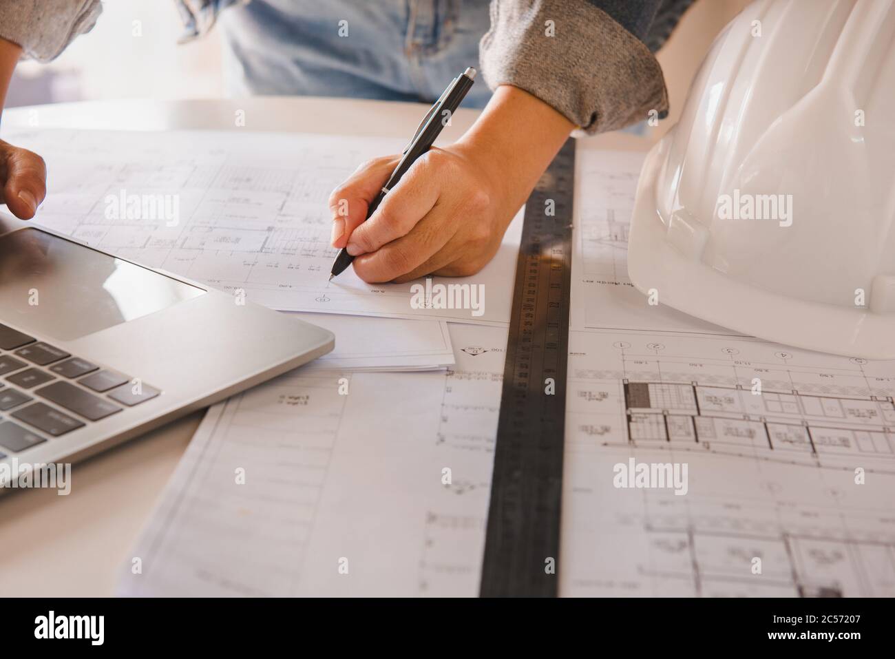 Ingenieure halten einen Stift zeigt auf ein Gebäude und Zeichnung Auflageplan als Leitfaden für Bauherren mit Details.Engineering und Bau Co Stockfoto