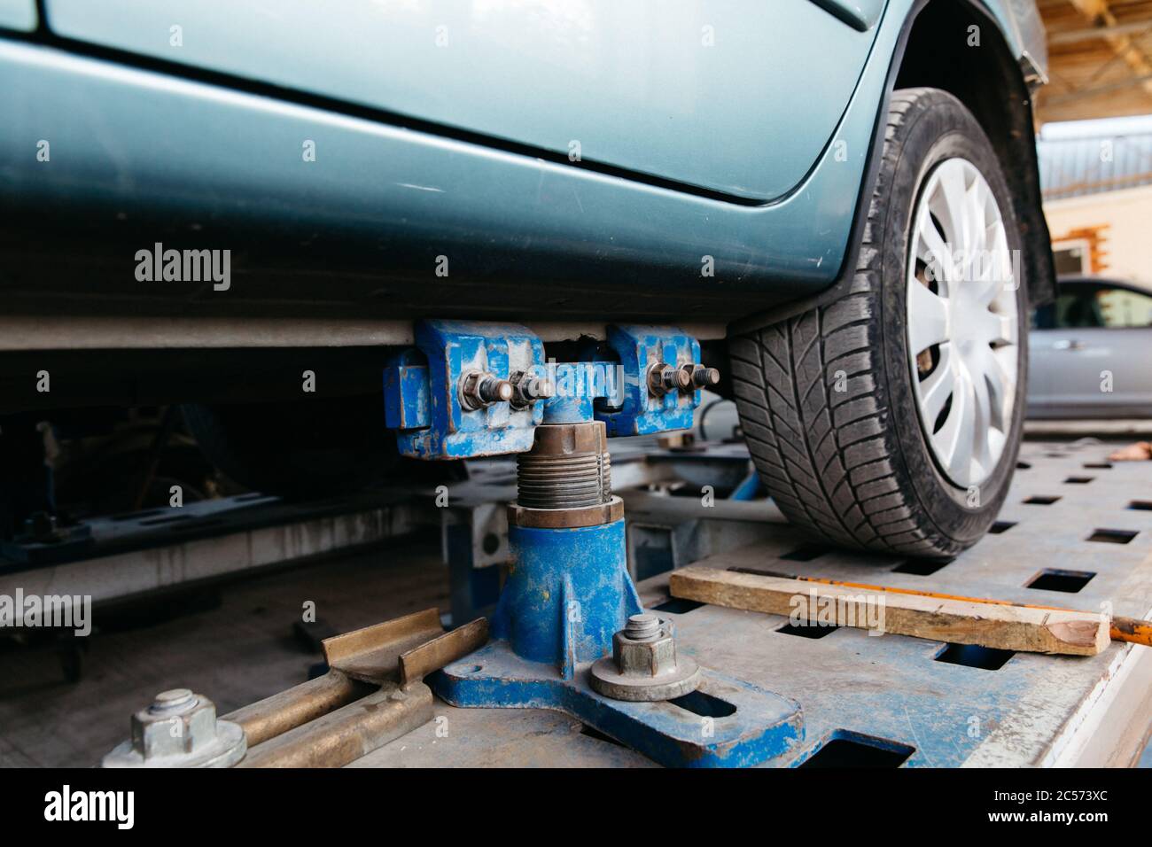 Ein blaues Auto wird zur Reparatur in einem Autoservice auf einen Aufzug gehoben. Stockfoto