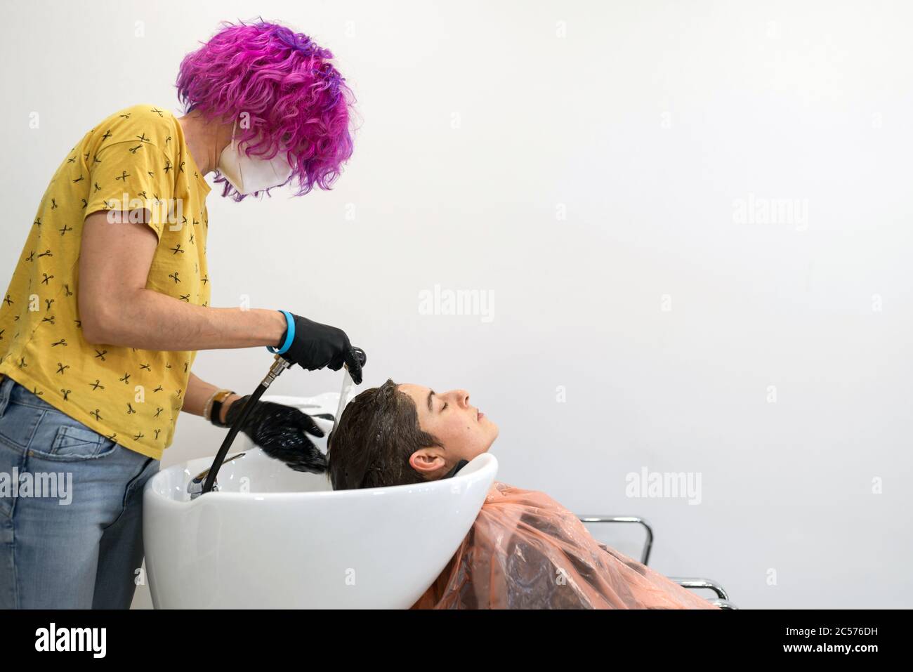 Konzept: Entbindung nach Coronavirus, covid-19. Professioneller Friseur mit  lila Haaren. Waschen Sie den Kopf einer Frau nach dem Schneiden ihrer Haare,  färben Stockfotografie - Alamy