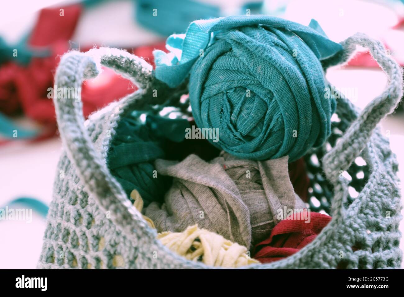 Nahaufnahme Ball aus Garn in der Tasche aus Recycling alten T-Shirt, Spaß Freizeit mit hausgemachten Wiederverwendung von geschnittenen Kleidung in Garnen, bunte Szene in Sonnenlicht Morgen Stockfoto
