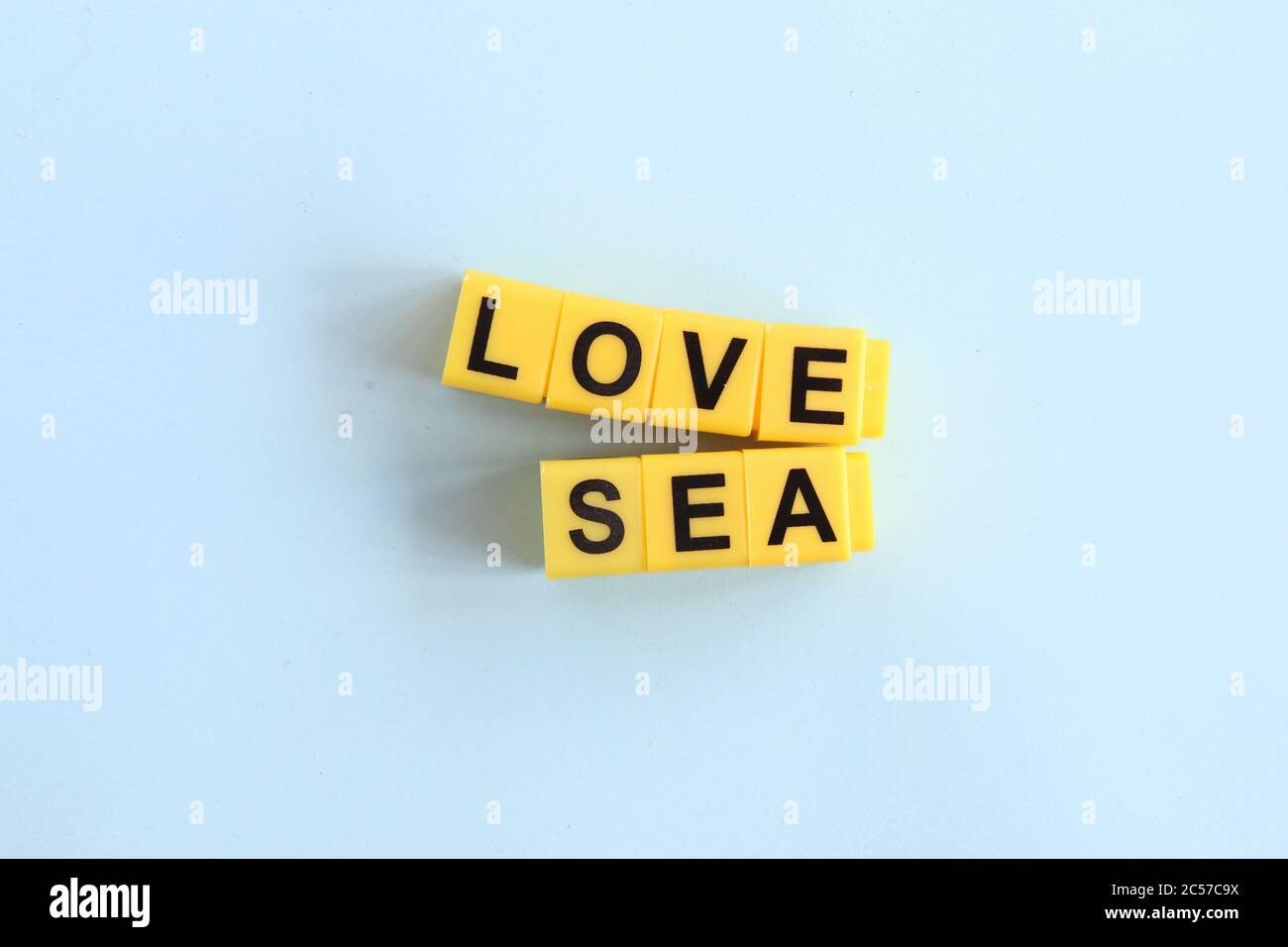 Love Sea Konzept, Schriftzug in gelben Buchstaben auf blauem Hintergrund Stockfoto Love Sea Konzept, Schriftzug in gelben Buchstaben auf blauem Hintergrund Stockfoto