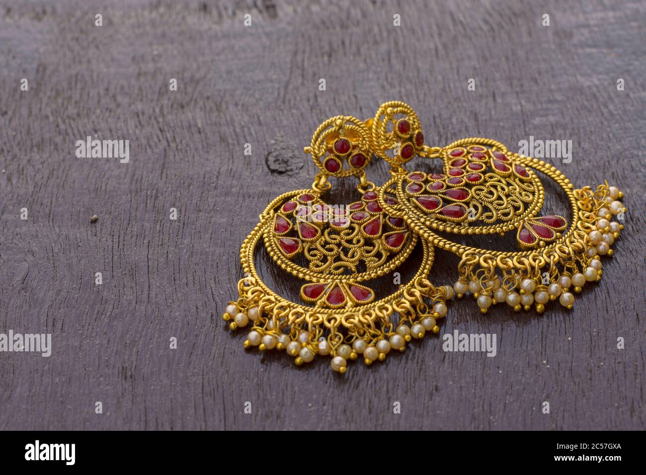 Goldener Ohrring mit schönem Design auf einer Holzoberfläche Stockfoto