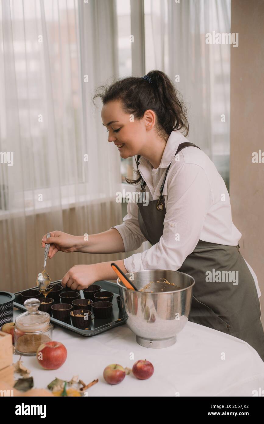 Der Bäcker schafft Cupcakes in Formen. Der Bäcker schafft Karotten Muffins. Stockfoto