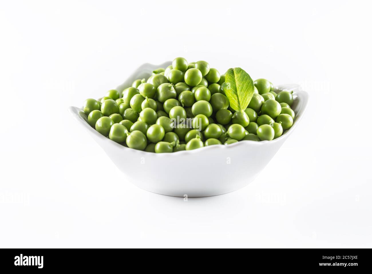 Grüne rohe Erbsen aus pobow Porzellan isoliert auf weißem Hintergrund Stockfoto