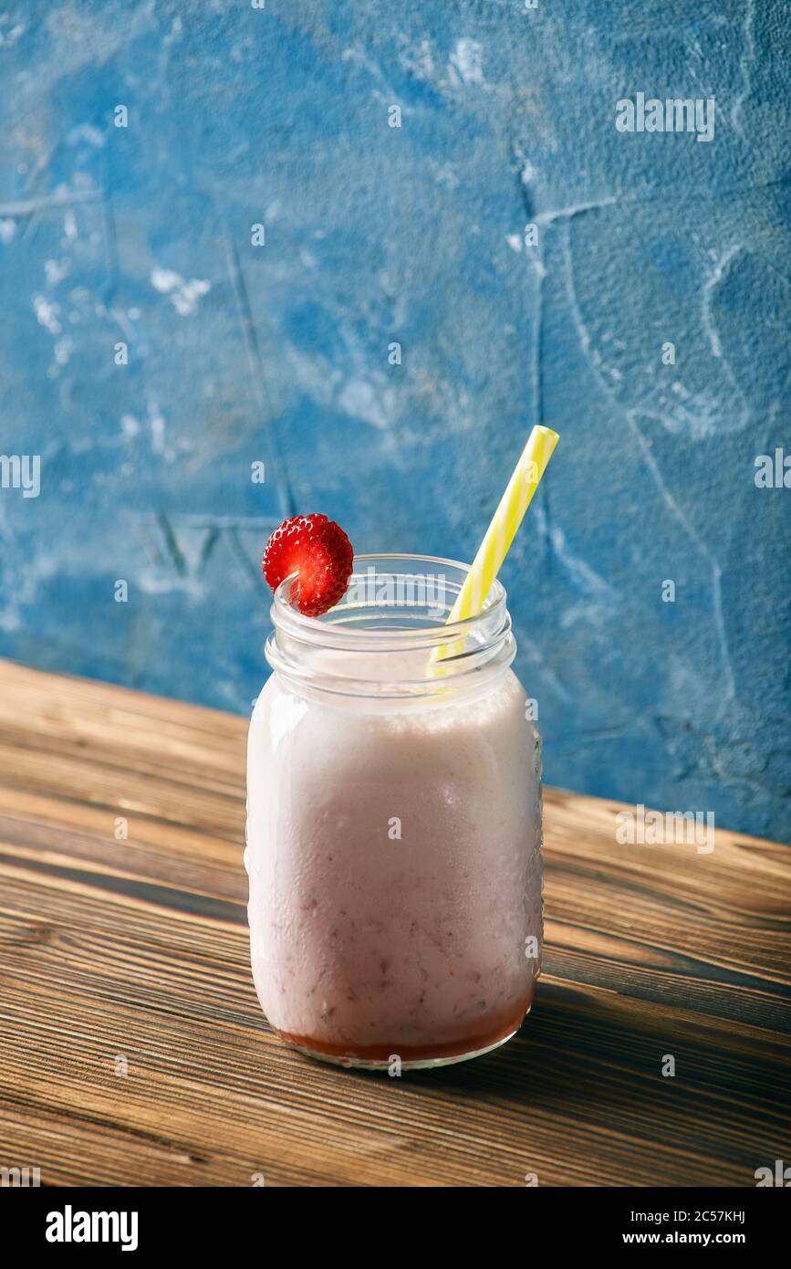 Erdbeer Smoothie auf einem Holztisch. Blauer Hintergrund Stockfoto