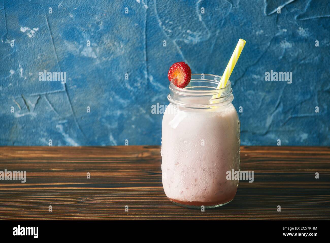 Erdbeer Smoothie auf einem Holztisch. Blauer Hintergrund Stockfoto