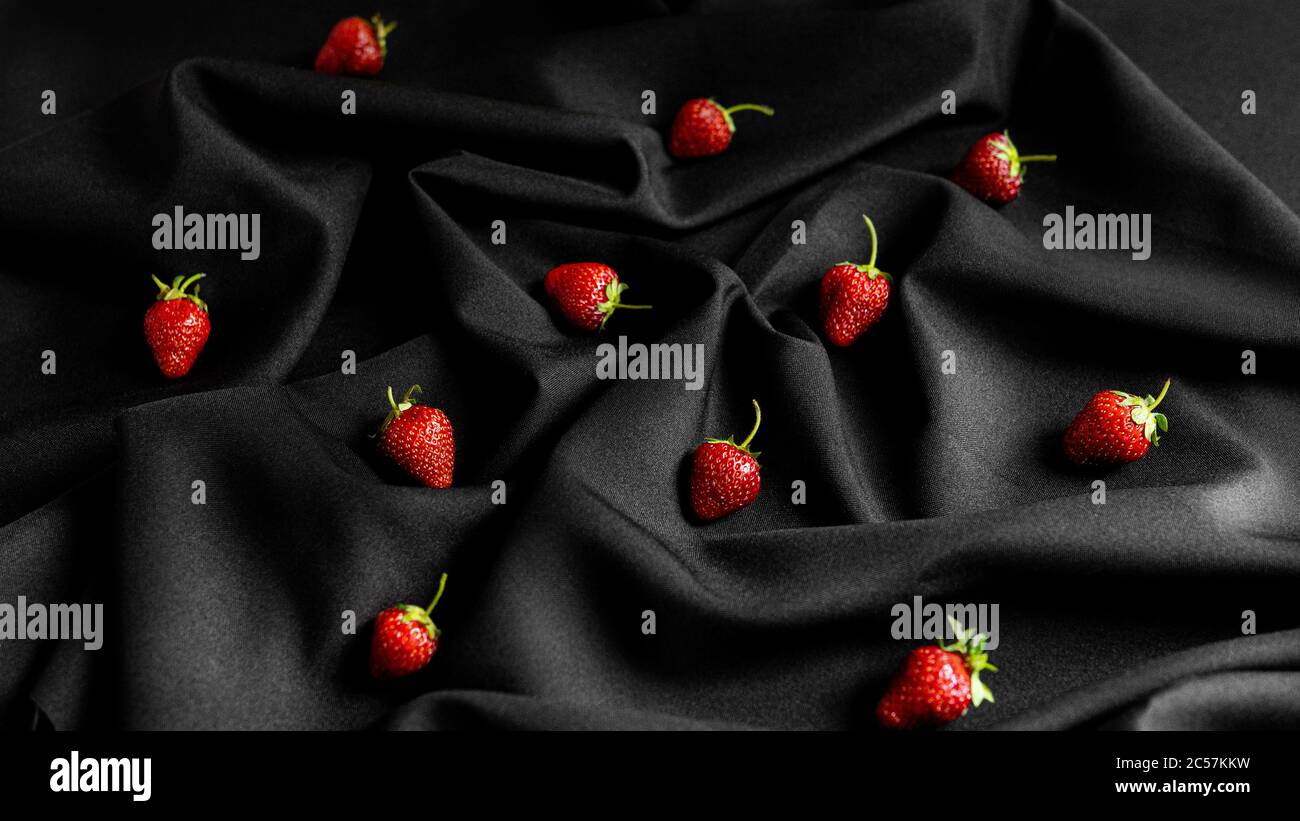 Erdbeeren auf schwarzem Stoffhintergrund. Schöne Kombination aus Rot und Schwarz Stockfoto