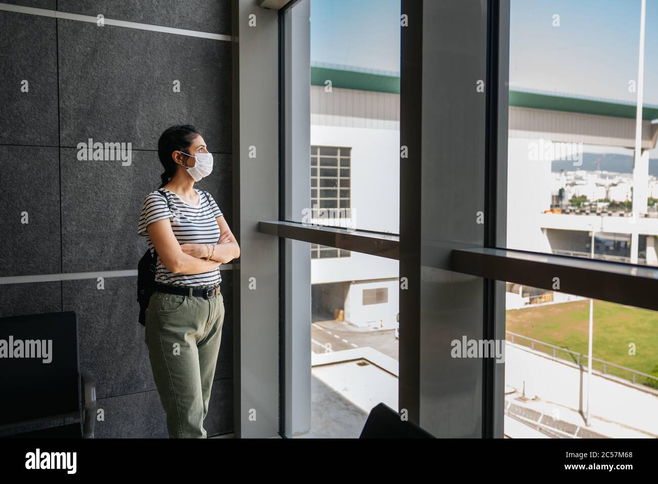 Die junge Frau steht in einer Wartehalle mit einer Schutzmaske. Corona Virus bricht aus. Hochwertige Fotos Stockfoto