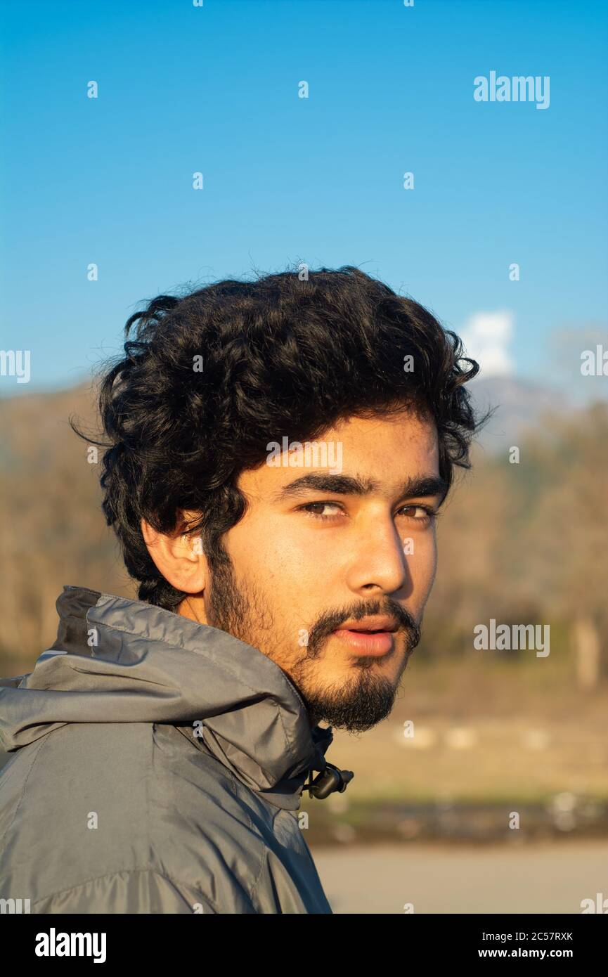 Porträt eines hübschen jungen Mannes, der eine Sportjacke trägt, die am Winterabend aufgenommen wurde. Blauer Himmel im Hintergrund. Hintergrund ist verschwommen. Er hat Gesichtsbehandlung Stockfoto