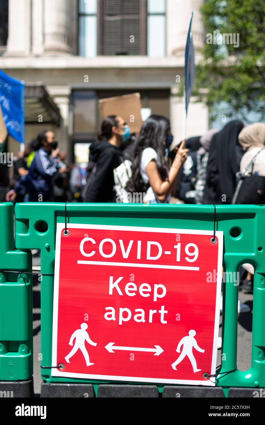 Social Distancing Road Signage beside a Black Lives Matter Demonstration, London, 27. Juni 2020 Stockfoto