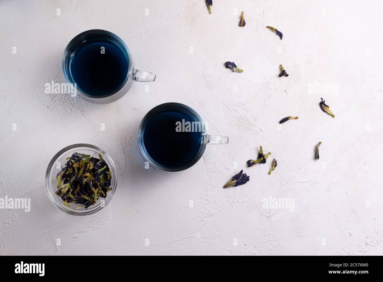 Anchan Thai blauer Tee in zwei Glas-Tassen und einer Schüssel mit trockenen Blumen. Schöne Indigo-Farbe. Speicherplatz kopieren. Draufsicht. Stockfoto