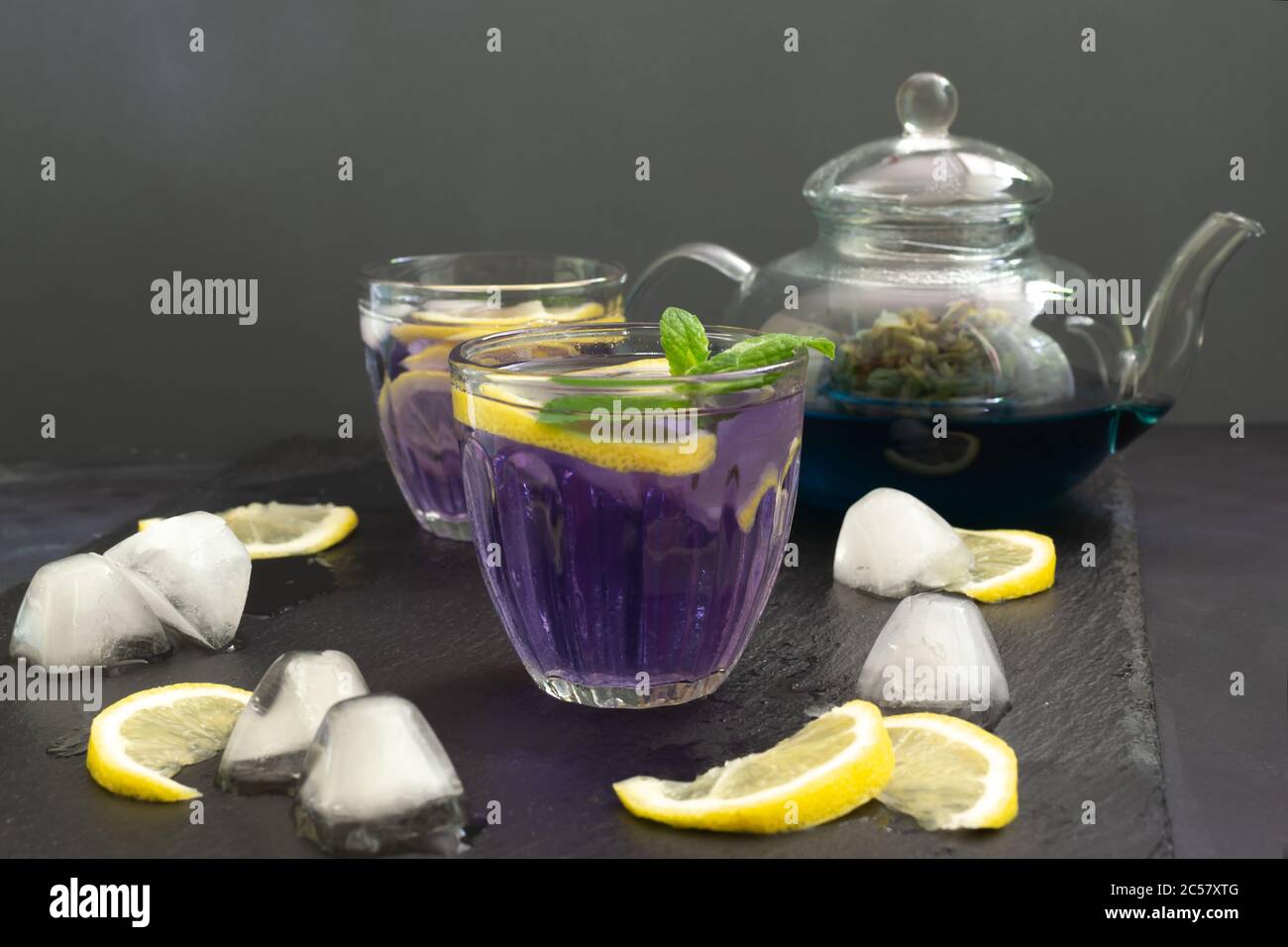 Kaltblauer Thai Anchan Tee in einer Glasschale mit Eis und Zitrone auf schwarzem Hintergrund. Speicherplatz kopieren. Stockfoto