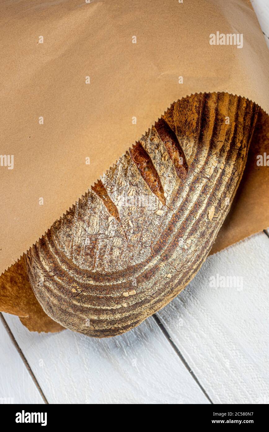 Frisch gebackener Sauerteig Brot in braunem Papierbeutel auf weiß getünchten Brettern Stockfoto